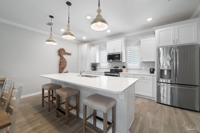 kitchen with an island with sink, stainless steel appliances, ornamental molding, a sink, and a kitchen breakfast bar