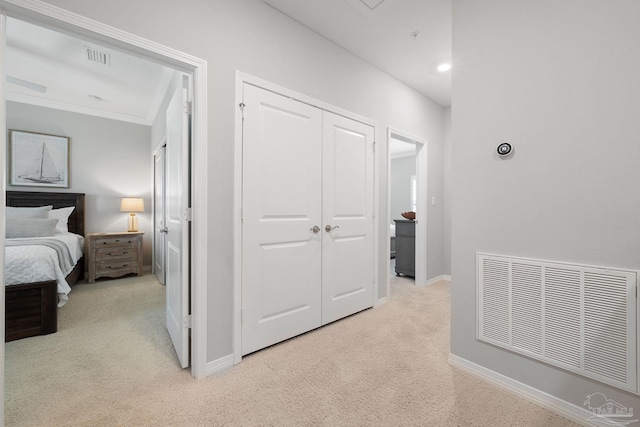 corridor featuring visible vents, baseboards, ornamental molding, and light carpet