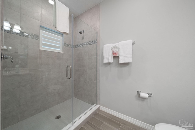 full bath featuring baseboards, a shower stall, and toilet