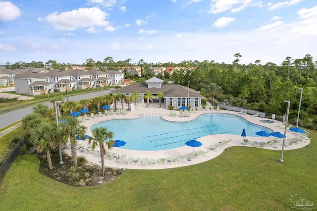 community pool featuring a patio area, a residential view, a hot tub, and a lawn
