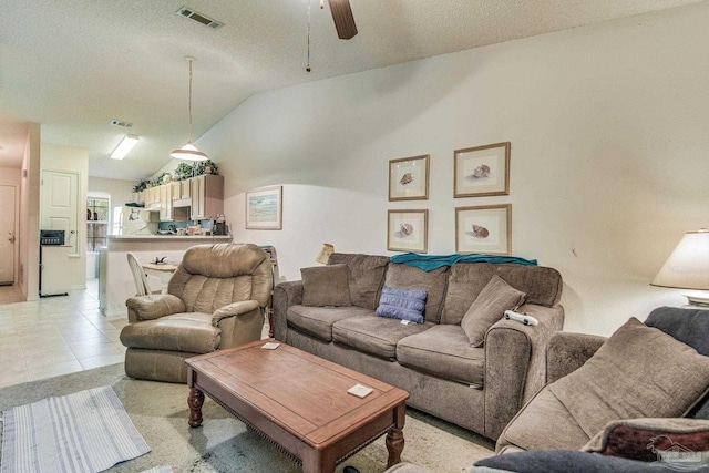 tiled living room featuring a textured ceiling, ceiling fan, and vaulted ceiling