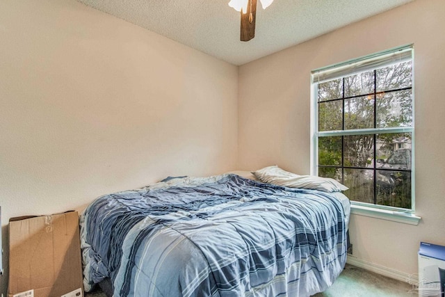 bedroom with ceiling fan, carpet, and a textured ceiling