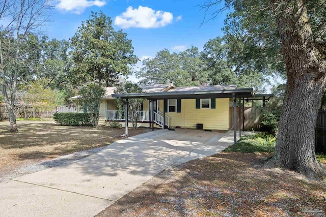 view of front facade with concrete driveway, a carport, and fence