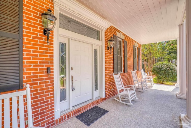 entrance to property with a porch and brick siding