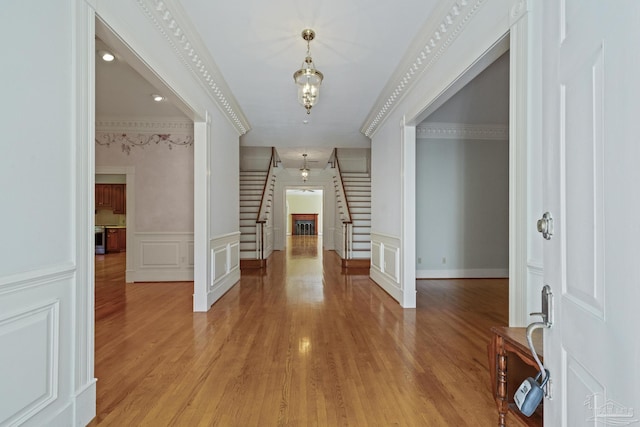 entrance foyer with stairway, light wood finished floors, wainscoting, and a decorative wall