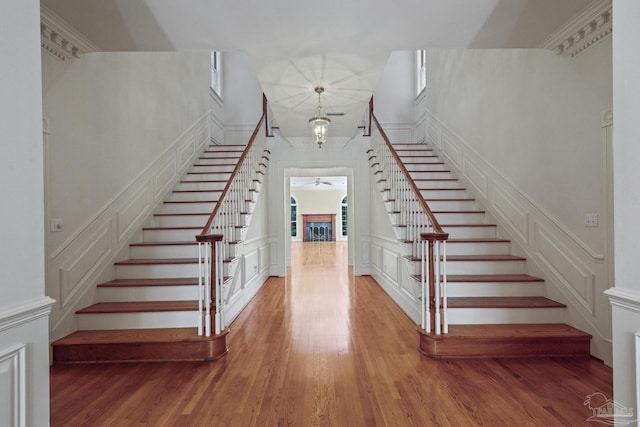 staircase with ornamental molding, a notable chandelier, a decorative wall, and wood finished floors