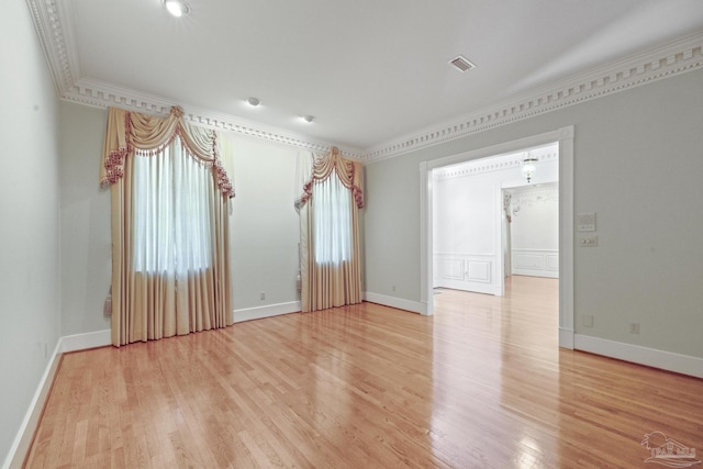unfurnished room with crown molding, baseboards, light wood finished floors, and visible vents