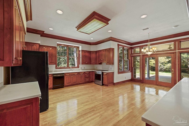 kitchen with a sink, a chandelier, ornamental molding, and black appliances