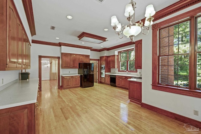 kitchen featuring a notable chandelier, light wood finished floors, a sink, black appliances, and light countertops