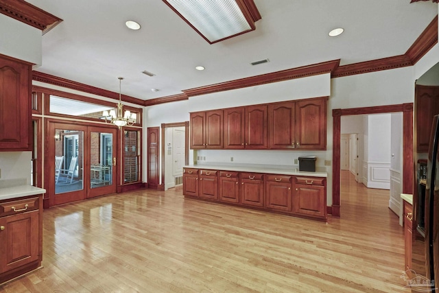 kitchen with pendant lighting, light countertops, ornamental molding, and a notable chandelier