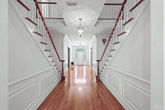 entrance foyer featuring ornamental molding, wood finished floors, visible vents, and stairway