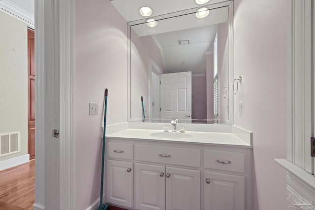 bathroom featuring baseboards, vanity, visible vents, and wood finished floors