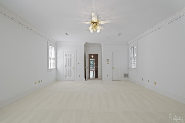empty room featuring a healthy amount of sunlight, ceiling fan, ornamental molding, and visible vents