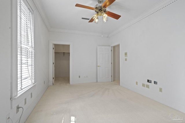 unfurnished bedroom with visible vents, crown molding, light colored carpet, and a walk in closet