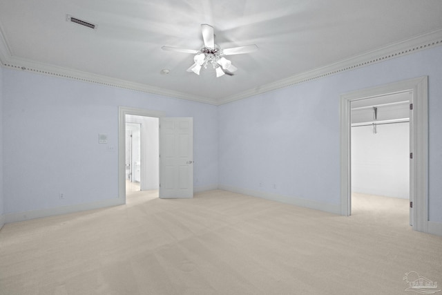 unfurnished bedroom featuring ornamental molding, visible vents, light carpet, a spacious closet, and a ceiling fan