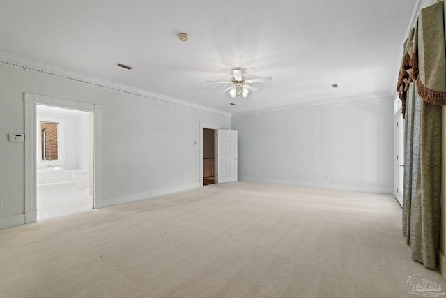 spare room with light colored carpet, visible vents, crown molding, ceiling fan, and baseboards