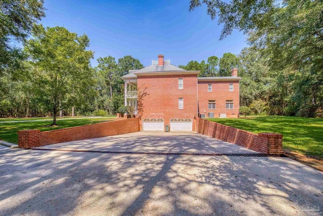 view of property exterior featuring an attached garage, driveway, a chimney, and a lawn