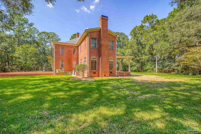 rear view of property with central AC unit, brick siding, a chimney, and a lawn