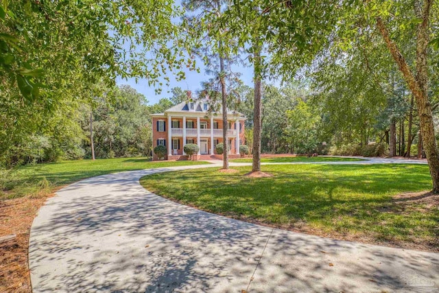 view of property's community featuring a lawn and curved driveway