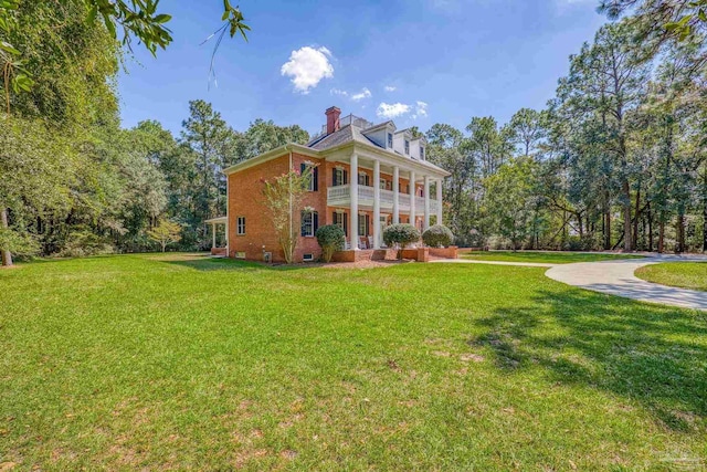 back of house featuring a yard, a chimney, and brick siding