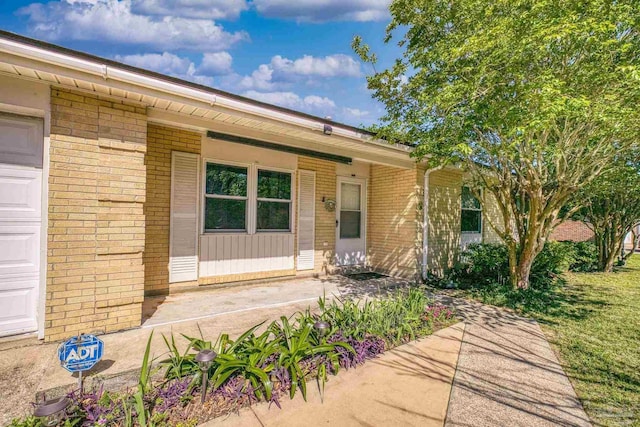 view of exterior entry with a garage and brick siding