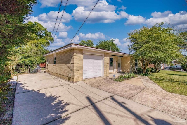 exterior space with driveway, an attached garage, brick siding, fence, and a lawn