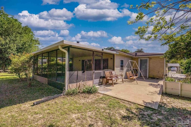 rear view of property with a patio area, a sunroom, and a lawn