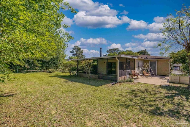 rear view of house with a patio, a yard, and a sunroom