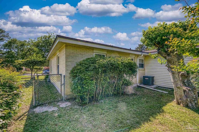 view of property exterior featuring central air condition unit, a gate, brick siding, fence, and a lawn