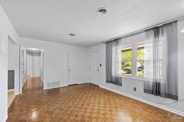 spare room featuring visible vents, baseboards, and a textured ceiling