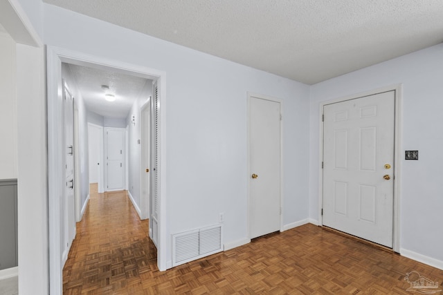 interior space featuring visible vents, a textured ceiling, and baseboards