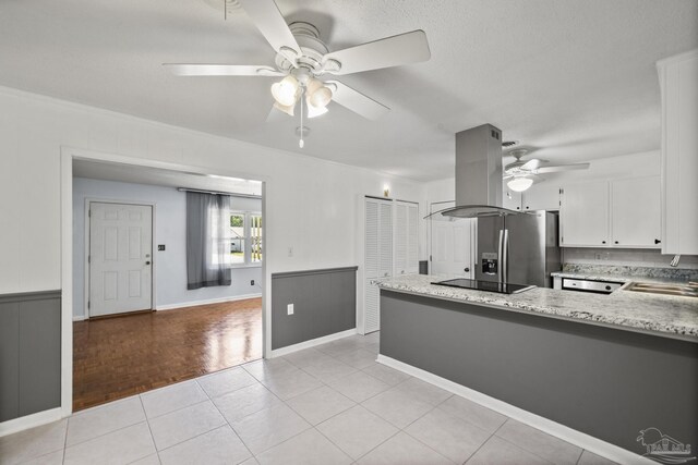 kitchen featuring island exhaust hood, a peninsula, white cabinets, black electric cooktop, and ceiling fan