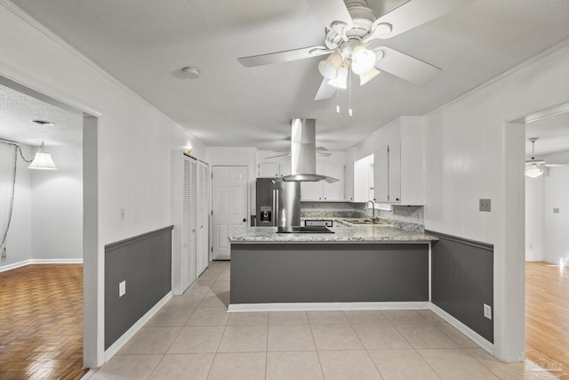 kitchen featuring stainless steel fridge with ice dispenser, a sink, a ceiling fan, a peninsula, and island range hood