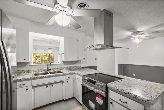 kitchen featuring wall chimney exhaust hood, a sink, a ceiling fan, and appliances with stainless steel finishes