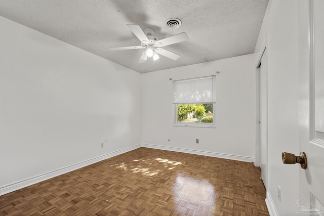 spare room with a textured ceiling, ceiling fan, baseboards, and visible vents
