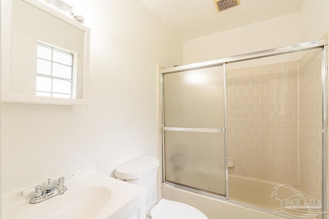 full bathroom featuring vanity, combined bath / shower with glass door, and toilet