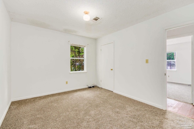 carpeted empty room featuring a textured ceiling