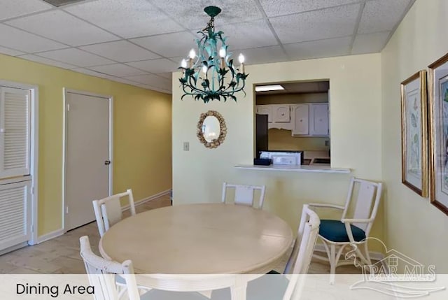 999 Ft Pickens Rd Unit 108, Pensacola Beach, FL 32561 - dining space featuring a paneled ceiling, a chandelier, and baseboards