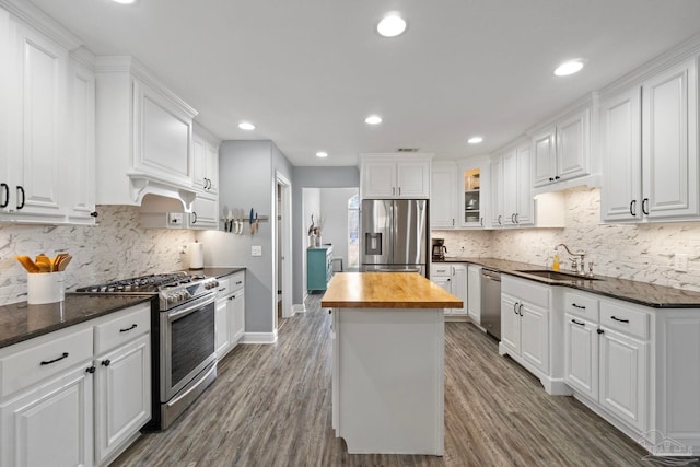 kitchen with hardwood / wood-style floors, butcher block counters, sink, appliances with stainless steel finishes, and white cabinetry