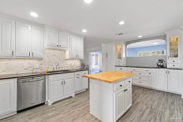 kitchen with white cabinets, butcher block countertops, stainless steel dishwasher, and sink