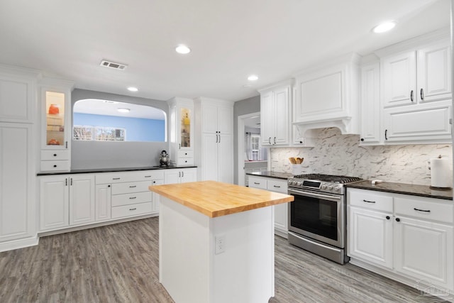 kitchen with stainless steel range, butcher block countertops, and white cabinets