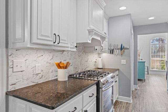 kitchen featuring tasteful backsplash, light hardwood / wood-style flooring, dark stone countertops, high end stainless steel range, and white cabinets