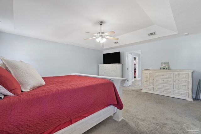 carpeted bedroom with a tray ceiling and ceiling fan