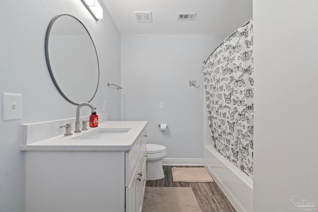 full bathroom with hardwood / wood-style floors, vanity, shower / tub combo, and toilet