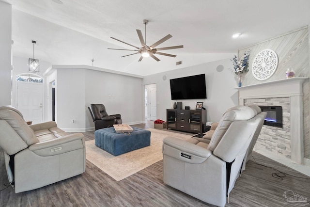 living room featuring a stone fireplace, ceiling fan, hardwood / wood-style floors, and lofted ceiling