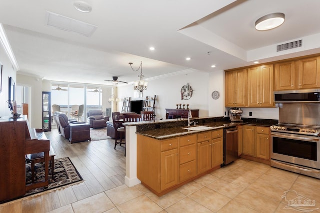 kitchen with kitchen peninsula, stainless steel appliances, dark stone countertops, and sink