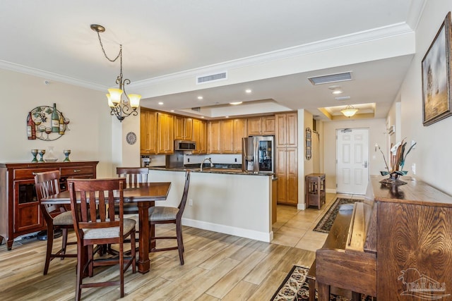 dining room featuring an inviting chandelier, a raised ceiling, crown molding, and sink