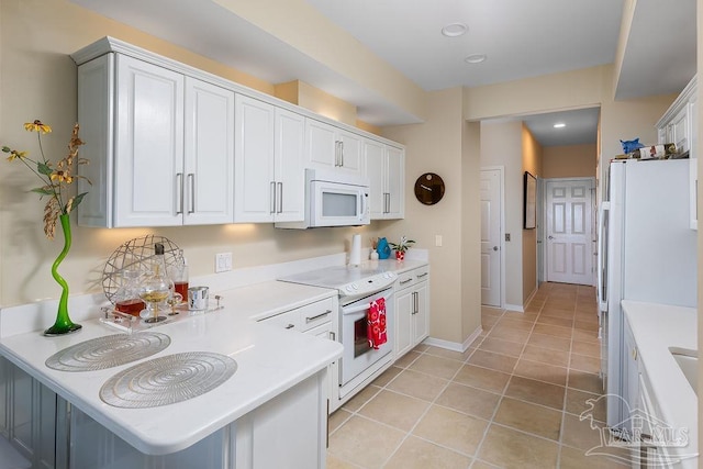 kitchen featuring a kitchen breakfast bar, white appliances, kitchen peninsula, white cabinets, and light tile patterned flooring