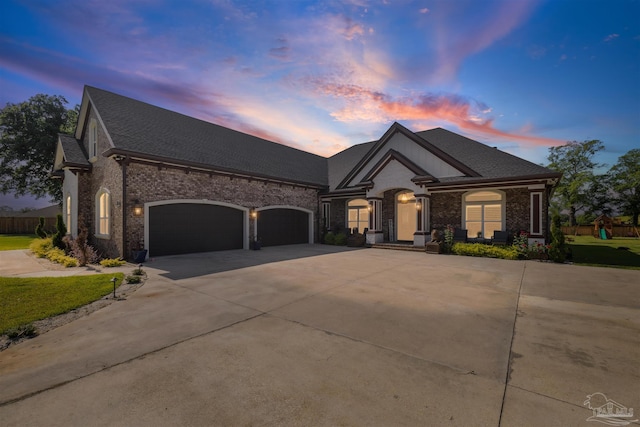 6126 E Fence Rd, Pensacola, FL 32526 - french country home featuring concrete driveway, an attached garage, brick siding, roof with shingles, and a lawn