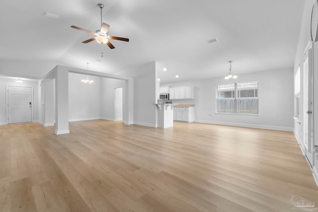 unfurnished living room with ceiling fan with notable chandelier, vaulted ceiling, and light hardwood / wood-style flooring